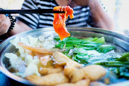 用筷子夹着牛肉片的女人涮锅是韩国或日本风格的牛肉图片