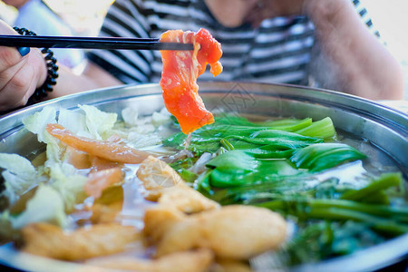 用筷子夹着牛肉片的女人涮锅是韩国或日本风格的牛肉图片