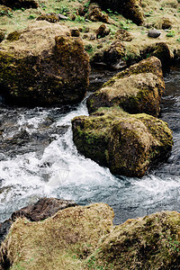 紧贴山河水流绿黄草和石块在冰岛的岩壁上图片
