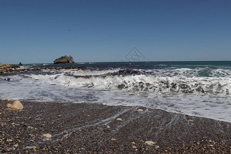 浪花塞浦路斯西北部美丽的卵石海滩以及美丽的岩石纪念碑各种颜色的石头在涨潮时闪发光天蓝色在背景