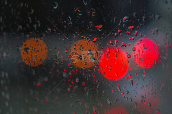 望向雨下街道的窗口路面明亮的夜晚天气汽车玻璃上的滴水和汽车上的bokeh图片