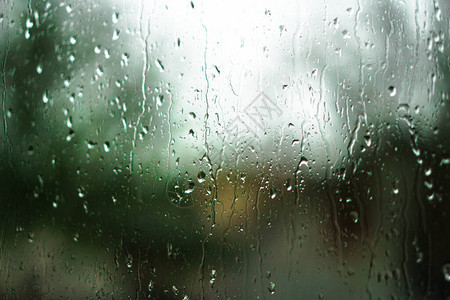 望向雨下街道的窗口路面明亮的夜晚天气汽车玻璃上的滴水和汽车上的bokeh图片