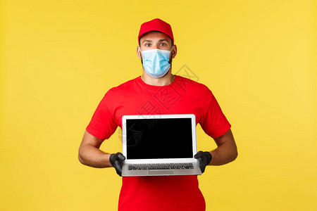 穿着红色制服和医用面罩的快递员在笔记本电脑屏幕上展示了令人惊叹的广告图片