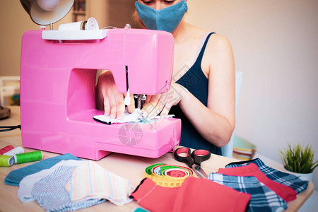 使用缝纫机制作时尚面罩以预防和阻止冠状传播的女图片