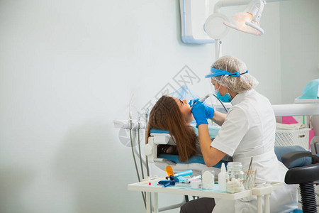 女牙医用蓝色手套和防护面罩治疗牙腔牙医在牙科诊所办公室进行龋齿治疗人医学口腔医学和保健概图片