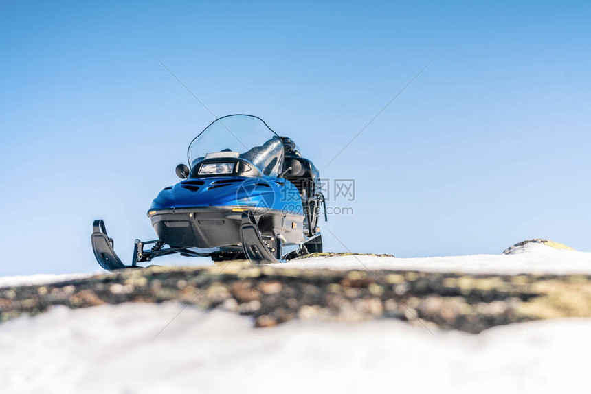 一辆蓝色的雪地摩托站在雪地上图片