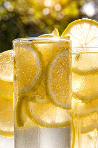 阳光明媚的花园背景上的柠檬水杯特写视图图片