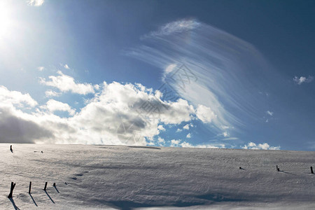 蓝色天空中美丽的云层在雪覆盖的田图片