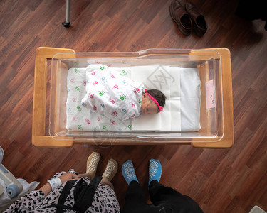 一个刚出生的女婴躺在一个用襁褓毯包裹的滚动摇篮车中图片