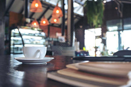 美式咖啡馆咖啡馆旧木制桌边的白咖啡杯热咖啡和笔背景
