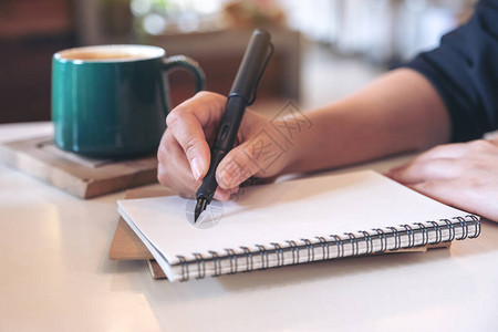 女手写在咖啡厅桌上咖啡杯空白笔记本图片