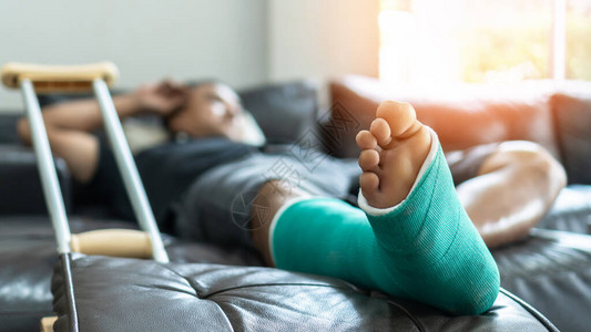 男病人在手术康复和整形疗养期间用石板和拐杖骨折的脚和腿骨图片