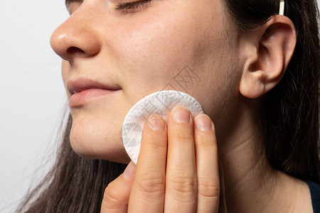一个30岁的妇女用一个棉垫擦脸图片