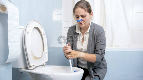 年轻女人洗脏厕所闭上鼻子图片