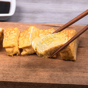木板上的日本玉冈煎蛋卷筷子拿着一块煎图片