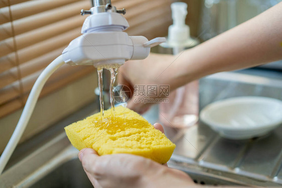 女人在黄色海绵上使用洗碗液关闭管家在水槽里洗脏盘子家政和日常作业概念图片