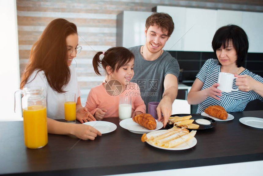 厨房里一个大家庭的快乐早餐兄弟姐妹父母和孩子母亲和祖母父亲和女儿每个人都在早上吃东西图片