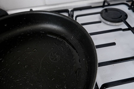 油腻的黑色煎锅留在煤气炉上烹饪后未洗的杂乱炊具导致肥胖的不健康的食物选择和生活方式厨房油炸图片