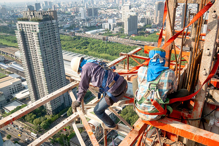 建筑工人穿戴标准个人防护设备在高层建筑工程图片