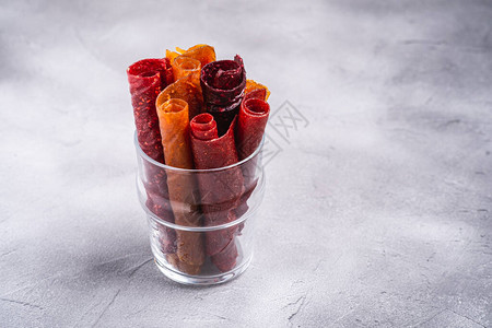 石混凝土背景玻璃杯中的水果锭剂由覆盆子草莓桃子和苹果制成的有机无糖卷起食品纯素自制糖图片