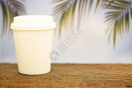 a咖啡杯在模糊棕榈叶背景的图片