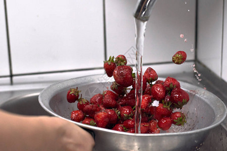 在厨房里洗草莓水果的妇女清洗和储存新鲜的菜图片