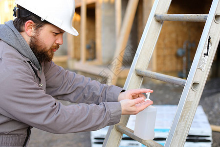 建筑工地上穿硬头巾和用消毒剂进行消毒的建筑工人图片