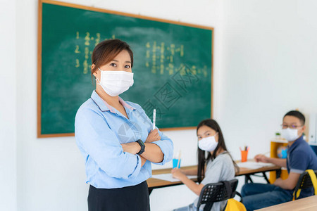 亚洲女教师戴口罩以防止Covid19在课堂上与学生一起爆发图片