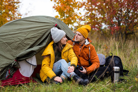 长途跋涉和徒步远足概念在秋林绿帐篷附近坐着爱情中的图片