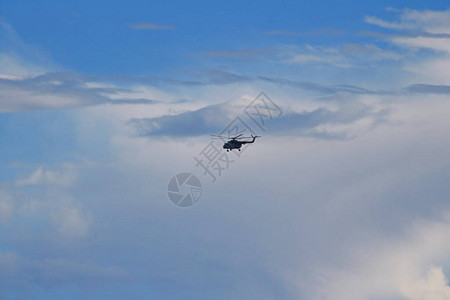 直升机在云层下的蓝天中飞行图片