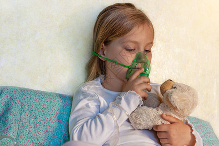小女孩在家里的床上用雾化器吸入生病的过敏儿童哮喘吸入器蒸汽咳嗽儿童过敏概念呼吸系统疾病肺部药物治疗季图片