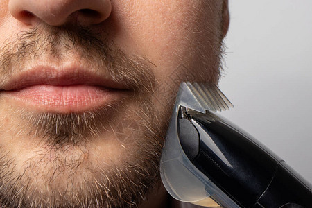 一个男人用剃须刀刮胡子造型胡子男风格面部毛发护理浴室的图片