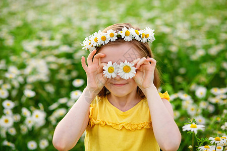 一个戴着雏菊花圈的风趣年轻女子笑着在她的眼前捧着鲜花图片