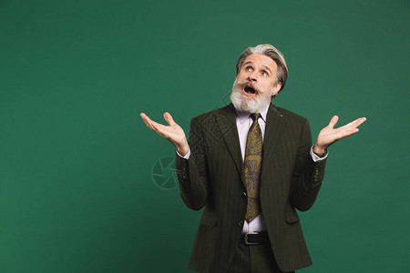 身穿卡其西服的中年大胡子男在绿色背景和复制图片