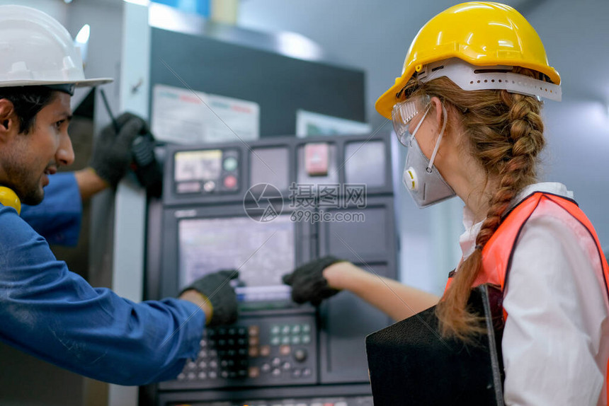 戴着面具的工厂女工指着机器的监视器与工程师一起在工作场所讨论工业企良好管图片