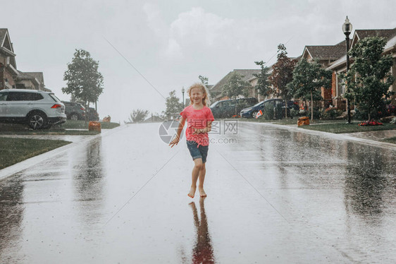 可爱的可爱女孩在街上的雨中奔跑孩子在阵雨风暴期间玩得开心孩子们的季节夏季户外活动自由和快乐的图片