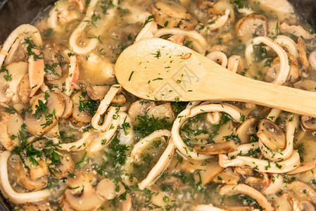 将切好的鱿鱼圈和蘑菇莳萝和欧芹放在平底锅里炖图片