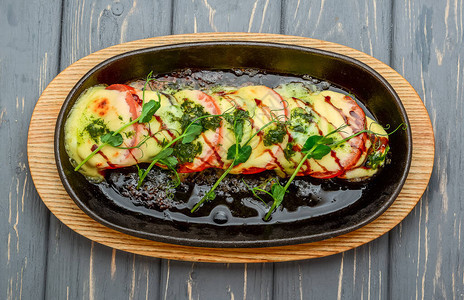 烤卡普雷塞鸡配马苏里拉奶酪罗勒和西红柿木制背景图片