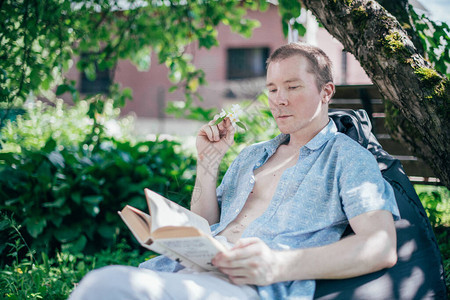 一个男人正在花园里的脚凳上休息和阅读休息日和放松阳光明媚的日子里图片
