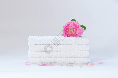 四条白色整齐折叠的毛巾有一朵玫瑰图片