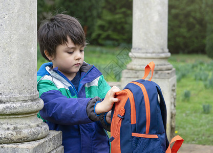 肖像学龄前男孩在森林公园冒险后打包背图片
