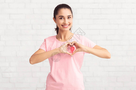 乳腺癌站在白色背景上的粉红色t恤上的志愿者妇女手势图片