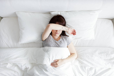 失眠和压力及失眠概念少女躺在床上用手遮图片
