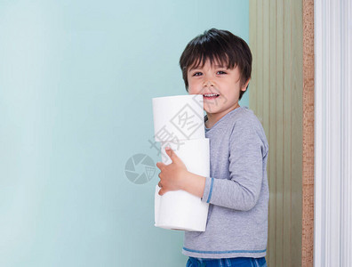 可爱的孩子拿着卫生纸站在马桶前的侧视肖像图片