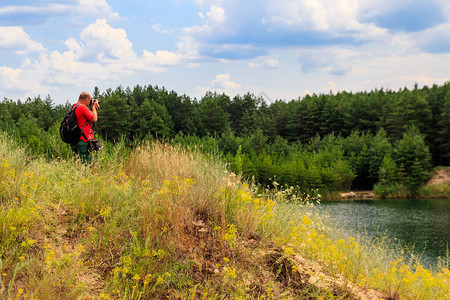 带背包的年轻旅行者在湖里拍照旅行摄图片