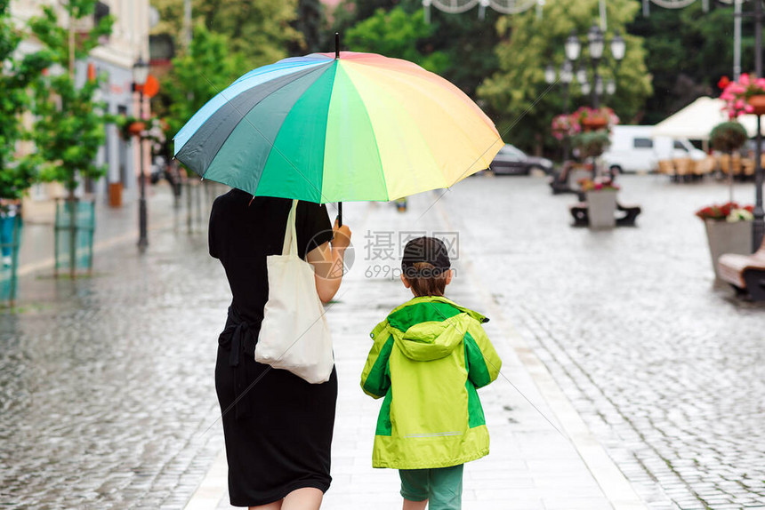 有雨的夏日在雨天散步的幸福家庭有大五颜六色的彩虹伞的母亲夏天的雨天在城图片