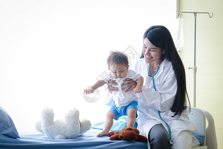 女医生在诊所检查亚裔小男孩病人的病床情况图片