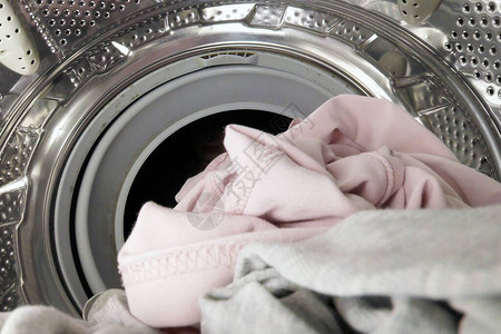 不知名的女人把衣服放在洗衣机里在洗图片