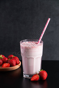 黑色背景的鲜奶昔和草莓夏季饮料与玻璃中的吸管文本放在何处图片