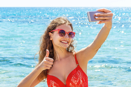 穿红色泳衣的年轻女子在海面背景中自画图片